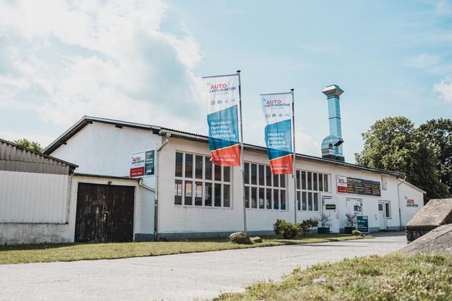 Werkstatt Auto-Lack-Doktor in Koitzsch – Außenansicht mit Fahnen